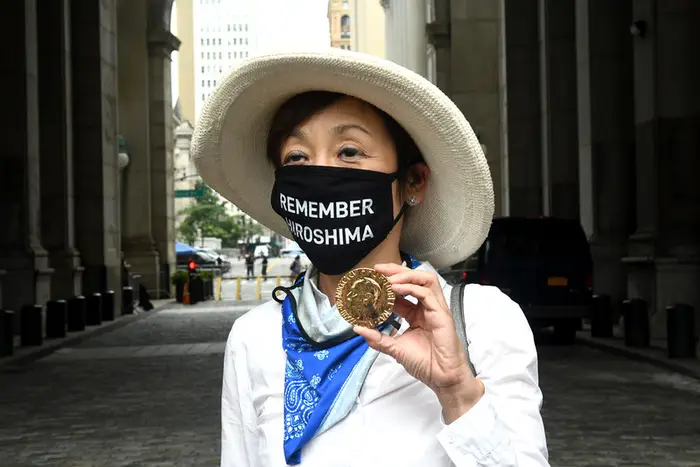 A woman wears a face mask saying "Remember Hiroshima" at a press conference urging the NY City Council to pass legislation to abolish Nuclear Weapons.